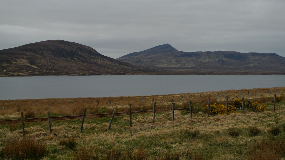 ​Loch an Ruathair with railway track in foreground and mountains on the horizon