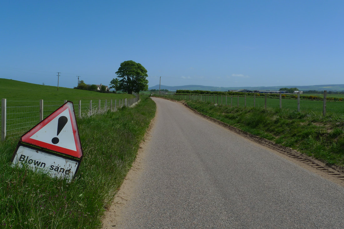 A sign warning of blown sand on a road near Spey Bay