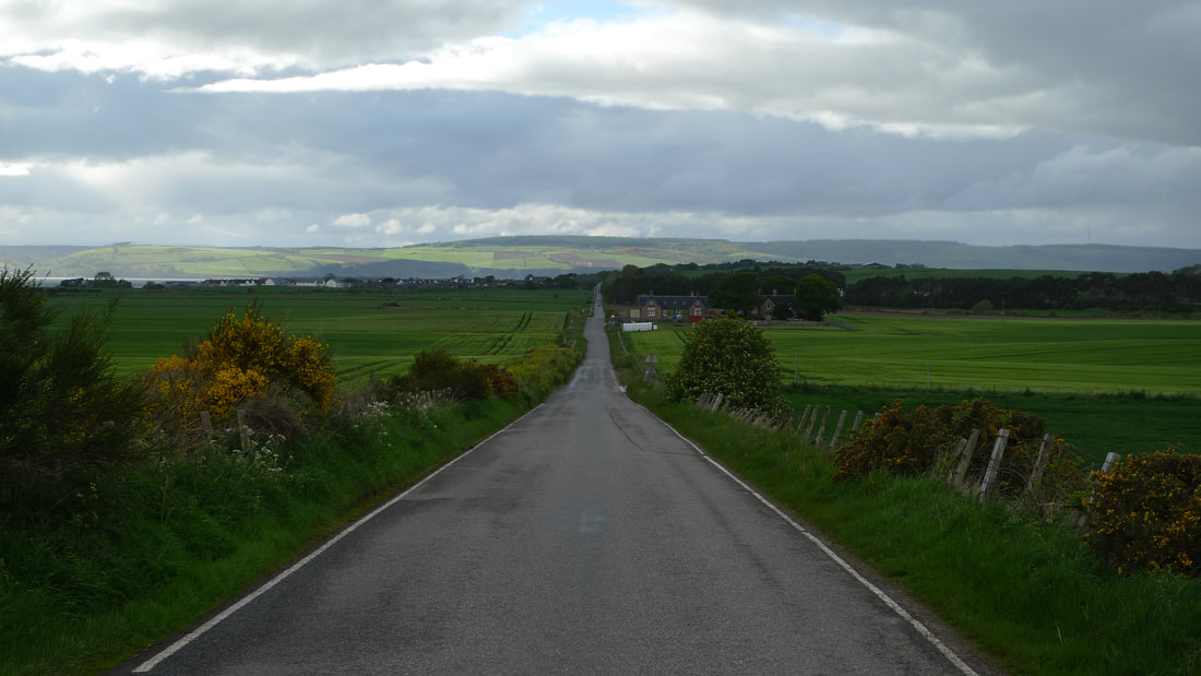 The B9006 road with hills on the horizon and fields each side