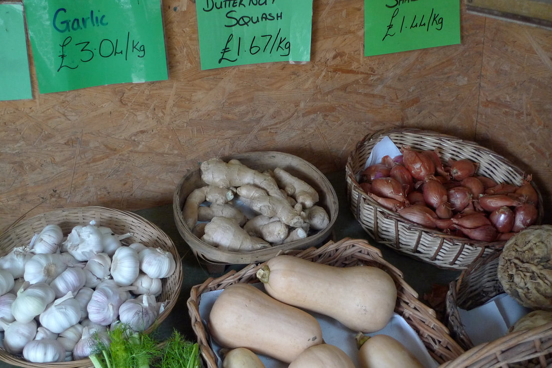 Tampilan sayuran dalam keranjang di Milton of Haugh Farm Shop.  Ada bawang putih, bawang merah, jahe, dan butternut squash