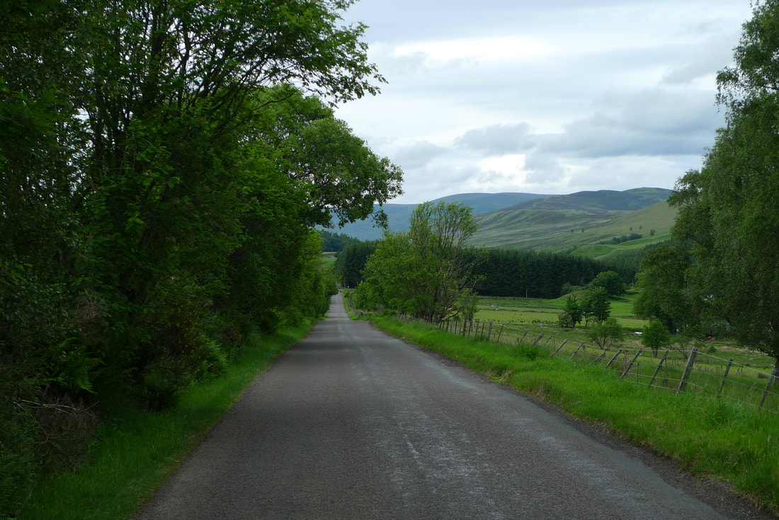 Jalan di Glen Clova dengan pegunungan Cairngorm di cakrawala