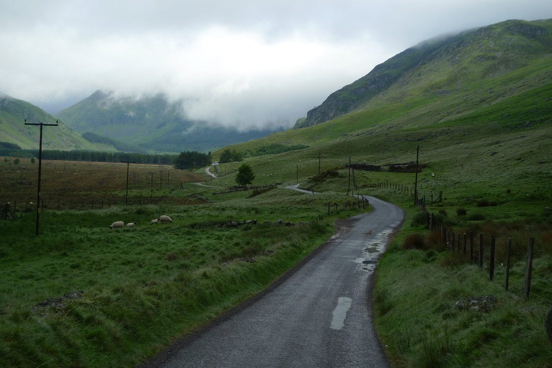 A winding road through Glen Doll. There is mist covering some of the hills