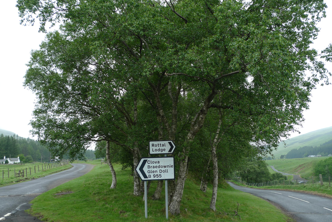 The junction in Glen Clova, a road sign points Rottal Lodge for the road on the right and the other sign says Clova. It points to the road on the left.