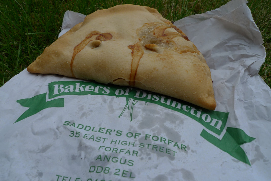 A Forfar Bridie dripping with meat gravy, its resting on a bag with the name of Saddler's bakery on it
