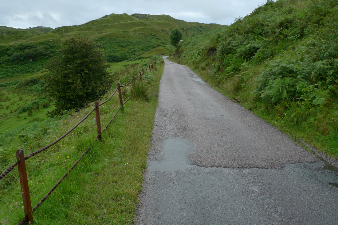 A road on the Isle of Luing with a green hill at the end