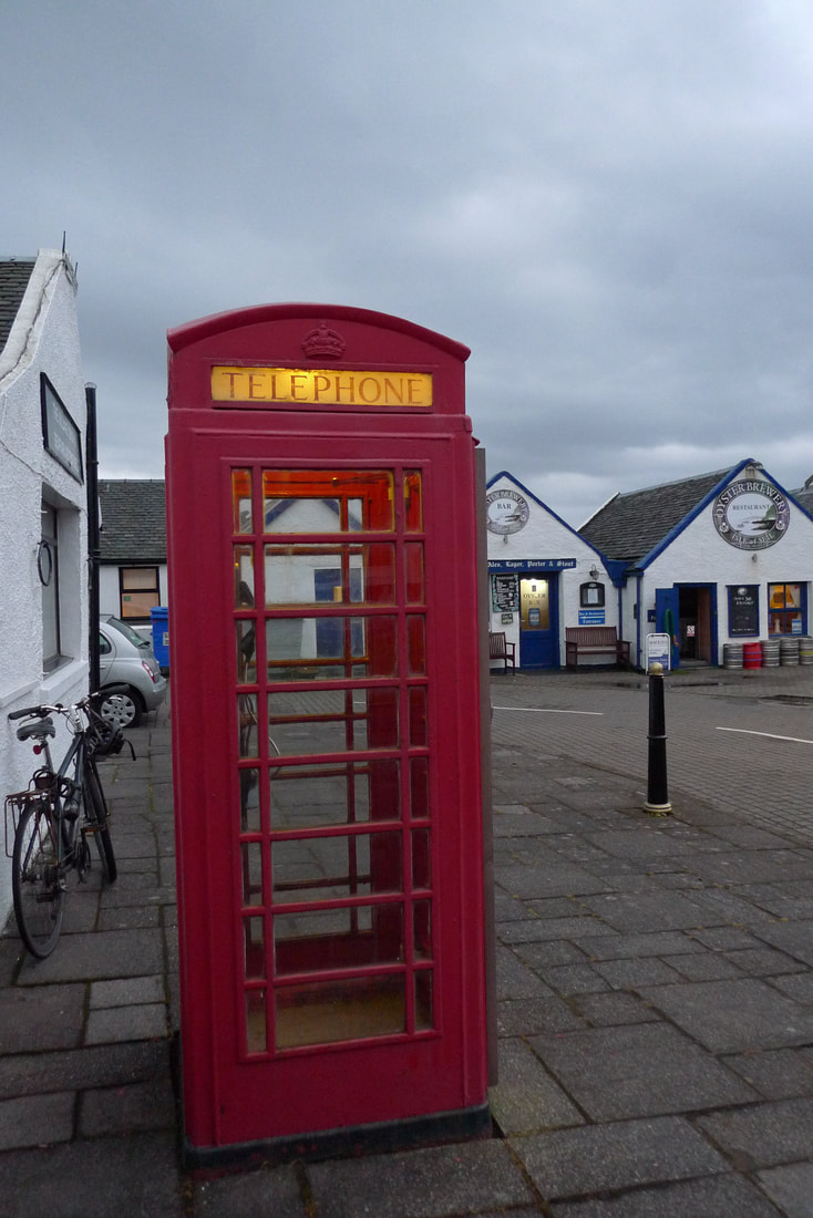 Red telephone box in Ellenabeich with the Oyster Bar in the background