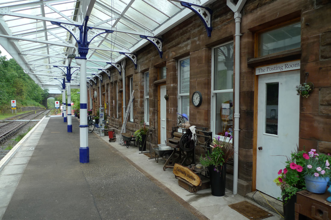 Dalmally station platform with an iron and glass canopy. The platform is decorated with plant pots.
