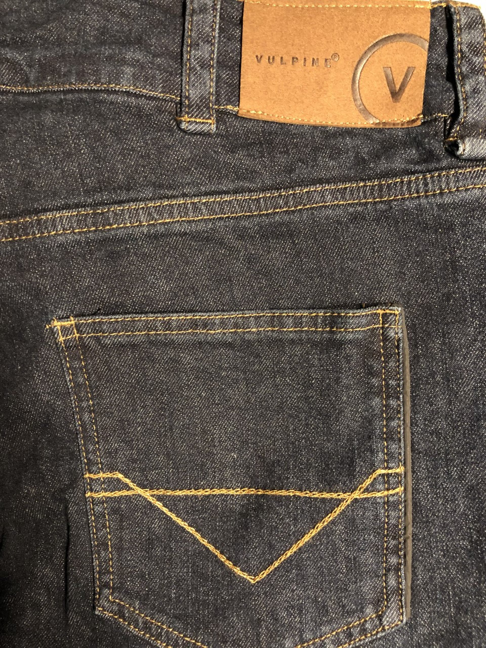The rear pocket of the Vulpine cycling jean. It has the Vulpine logo where the belt hoops are and the pocket has a V shaped stitching